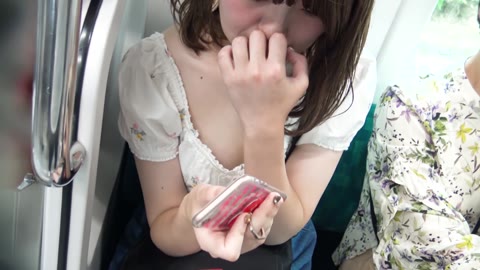 A fair-skinned, beautiful college girl, completely absorbed in her smartphone on the train, has her pink nipples fully exposed